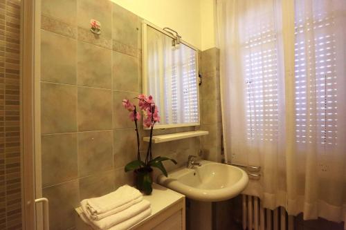 un bagno con lavandino e vaso con un fiore di monforte view apartment a Monforte dʼAlba
