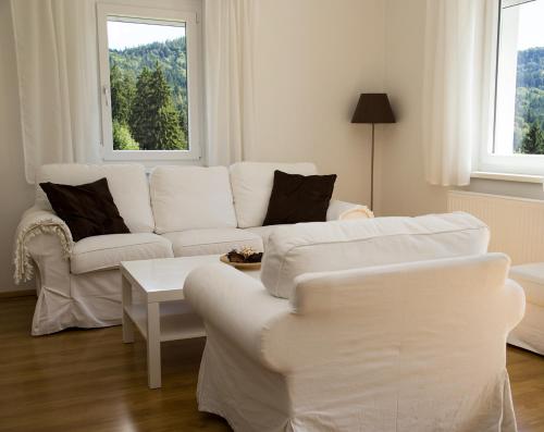 a living room with two white couches and a table at Apartments am Turiawald in Schiefling am See