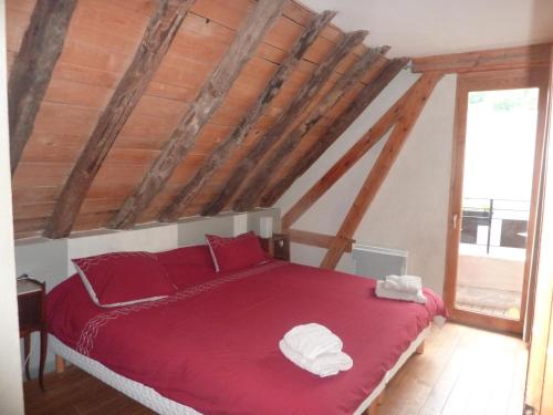 a bedroom with a red bed with two towels on it at la grange avec spa in Saint-Aventin
