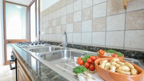 a kitchen counter with a sink with a bowl of vegetables at Villa Cigaline in Tiggiano