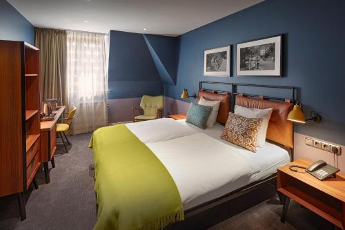 ein Hotelzimmer mit einem großen Bett und einem Schreibtisch in der Unterkunft Hotel Lion D'Or in Haarlem