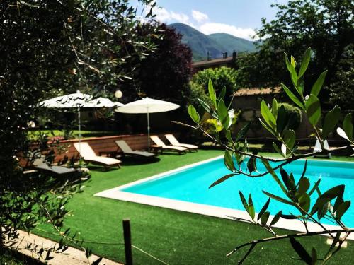 a swimming pool with chairs and umbrellas in a yard at Hotel Borgo Antico in Fabriano