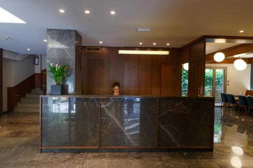 a woman is standing behind a counter in a lobby at Delice Hotel - Family Apartments in Athens