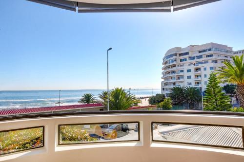 a balcony with a view of the beach and a building at Backup Powered Sea View Apartment on the Promenade in Cape Town