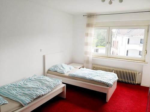 two beds in a room with a window at Work & Stay Leverkusen in Leverkusen