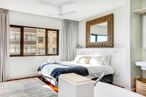 a bedroom with a bed and a mirror at Backup Powered Sea View Apartment on the Promenade in Cape Town