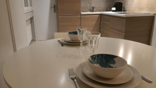 - une table blanche avec un bol et deux verres dans l'établissement Appartement de la Richelandiere, à Saint-Étienne