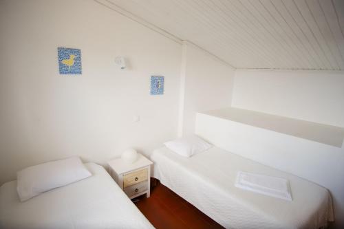 two beds in a room with white walls and wood floors at Apartamentos Pinhão in Lagos