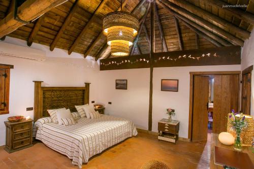 ein Schlafzimmer mit einem großen Bett und einer Holzdecke in der Unterkunft Ardea Purpurea in Villamanrique de la Condesa