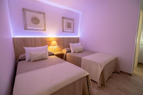 two beds in a room with purple lighting at Petit Malaga Congress in Málaga