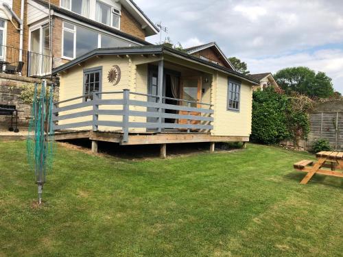 a small yellow house with a porch on a yard at Morlais Log Cabin in Lyme Regis