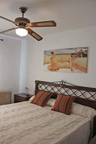 a bedroom with a bed with a ceiling fan at Apartamentos El Minarete in Roquetas de Mar
