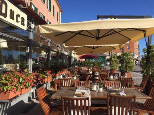 a restaurant with wooden tables and umbrellas at Hotel Gran Duca in Livorno