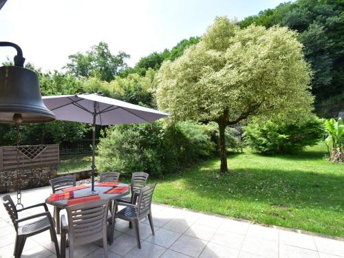 a patio with a table and chairs and an umbrella at Stone house with shared pool near Sarlat in Prats-de-Carlux