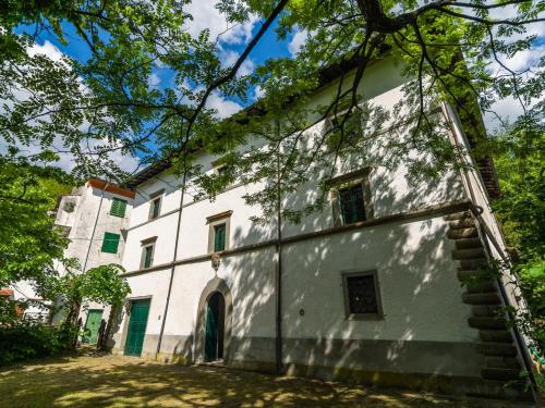 stary biały budynek z drzewami przed nim w obiekcie Belvilla by OYO l Antica Casa w mieście San Marcello Pistoiese