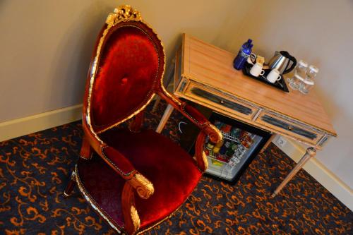a red chair sitting in a room with a table at Hotel Intourist Palace Batumi in Batumi