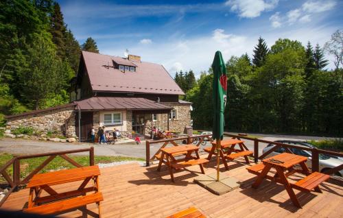 a group of picnic tables and benches on a deck at Horský Hotel Dobrá Chata in Stachy
