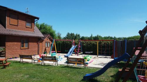 einen Hinterhof mit einem Spielplatz mit Rutsche und Schaukeln in der Unterkunft Diament Rogowo in Rogowo