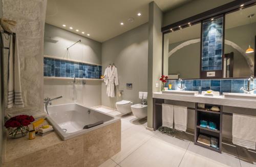 a bathroom with a tub and a toilet and a sink at Forte Village Resort - Villa Del Parco & Spa in Santa Margherita di Pula