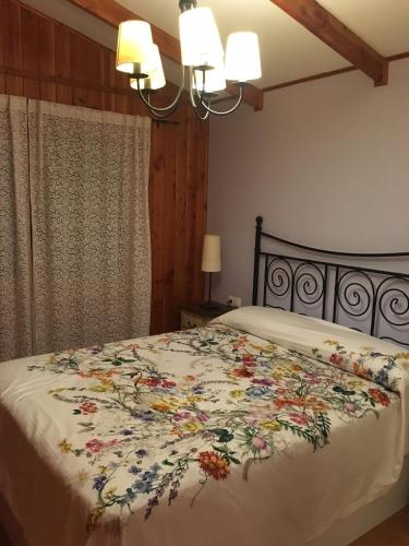 a bedroom with a bed with a floral bedspread at Casa-Apartamento Madera y Sol in Lubia
