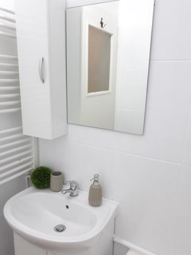 a white bathroom with a sink and a mirror at Studio Old Center in Bucharest
