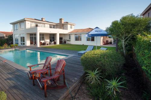 uma casa com piscina e duas cadeiras e um guarda-sol em Palamos on Sea em St Francis Bay
