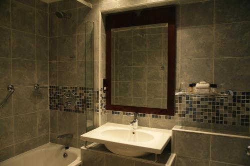 a bathroom with a sink and a tub and a mirror at The Imperial Torquay in Torquay