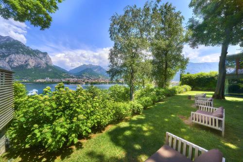 two benches in a park with a view of the water at Casa Sull'Albero in Malgrate