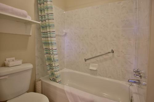 y baño con bañera, aseo y ducha. en Motel Exquise en Coaticook
