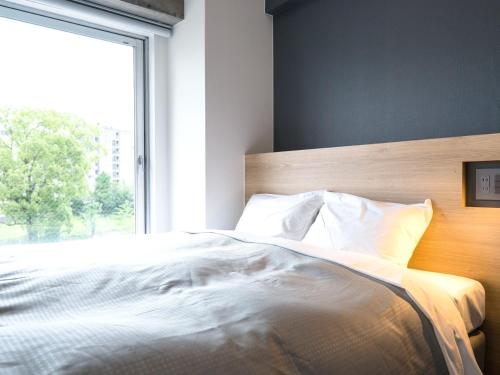 a bedroom with a bed with a large window at Resters Bed&Co. in Kumamoto