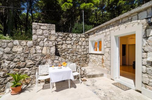 a table and chairs in front of a stone wall at Apartments & Rooms Tapera in Dubrovnik