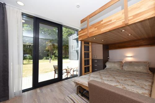 - une chambre avec un lit et des portes coulissantes en verre dans l'établissement Smilčių Apartment, à Palanga