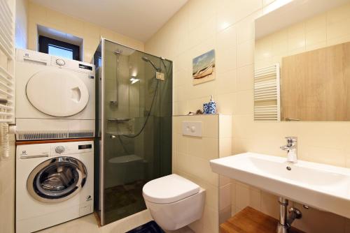 La salle de bains est pourvue d'un lavabo et d'un lave-linge. dans l'établissement Smilčių Apartment, à Palanga