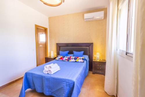 a bedroom with a blue bed with towels on it at Villa Puerto de la Torre in Málaga