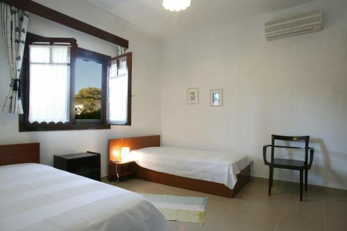 a bedroom with two beds and a chair and a window at Lagonisi Beach Resort in Ormos Panagias