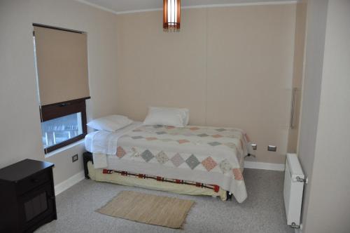 a small bedroom with a bed and a television at Andes Chillan Paraíso en la Montaña in Nevados de Chillan