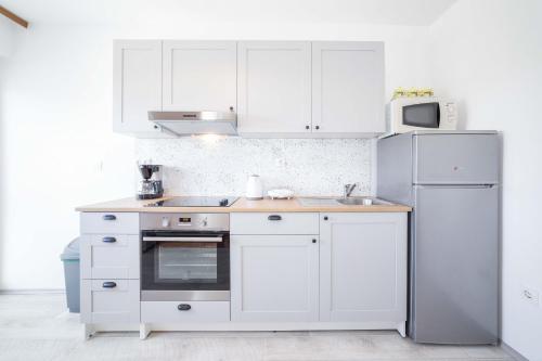 a kitchen with white cabinets and a white refrigerator at Apartments The heart of Croatia in Pirovac