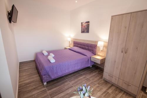 a small bedroom with a purple bed with purple sheets at Del Mar 'Adults Only' in Stalida