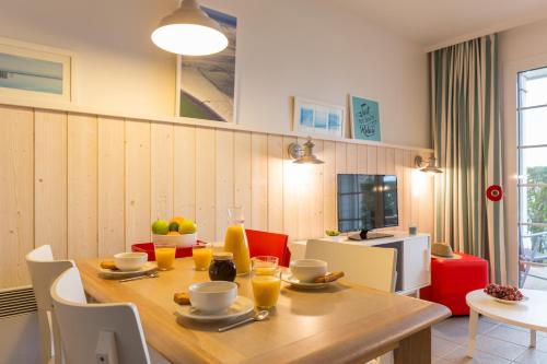 a dining room with a wooden table and chairs at Pierre & Vacances Premium Résidence de la Plage in Le Crotoy