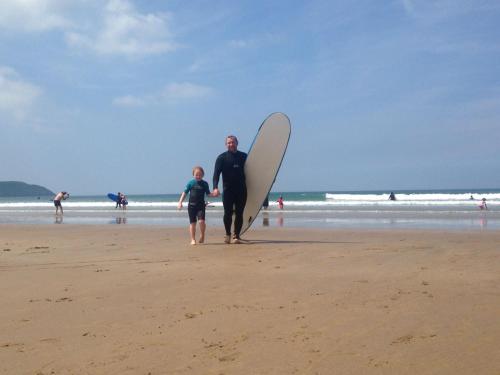 a man and a child walking on the beach with a surfboard at The Ocean Guest House in Weymouth