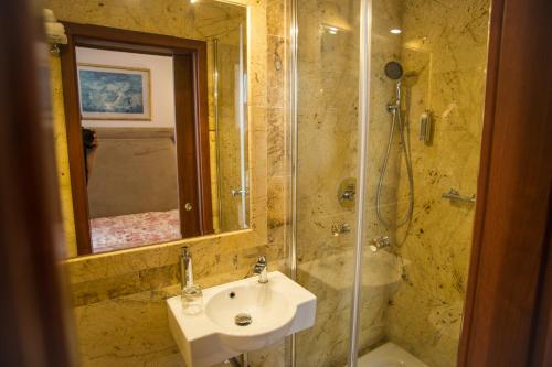 a bathroom with a sink and a shower with a mirror at Hotel Ambasada Bolesławiec in Bolesławiec