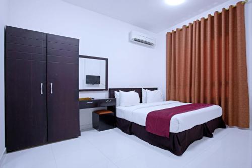 a bedroom with a bed and a dresser with a television at Alezz Suites Salalah in Salalah