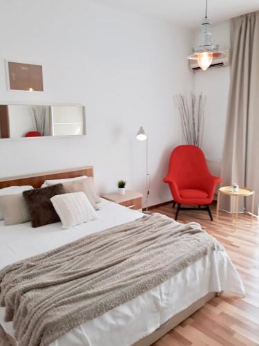 a bedroom with a large bed and a red chair at Studio Old Center in Bucharest