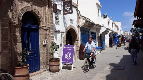 Ein Mann, der mit einem Schild auf einer Straße Fahrrad fährt. in der Unterkunft Casa Lila & Spa in Essaouira