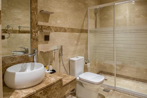 a bathroom with a toilet and a glass shower at Classical Hotel Suites in Jeddah