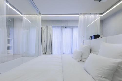 a hotel room with a white bed and white walls at The Grove Design Hotel in Tbilisi City