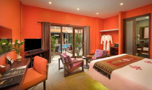 a bedroom with orange walls and a bed and a television at Golden Temple Hotel in Siem Reap