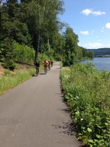 a group of people riding bikes down a road next to a river at JBX Resort Apartments Lipno in Lipno nad Vltavou