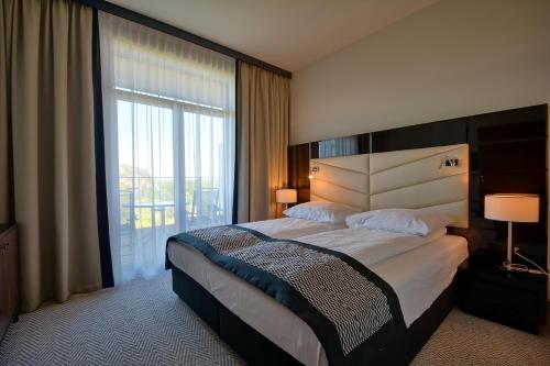 コウォブジェクにあるPrywatny apartament na wydmieのベッドと大きな窓が備わるホテルルームです。