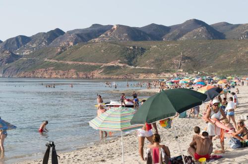 a crowd of people on a beach with umbrellas at Nel verde del Villaggio - Casetta Celeste in Gonnesa